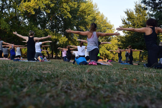 Outdoor yoga class demonstrating Alpha Omega Health benefits with participants stretching in a park