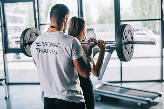 Personal trainer assisting a client with weights, showcasing the best equipment for home gym exercises