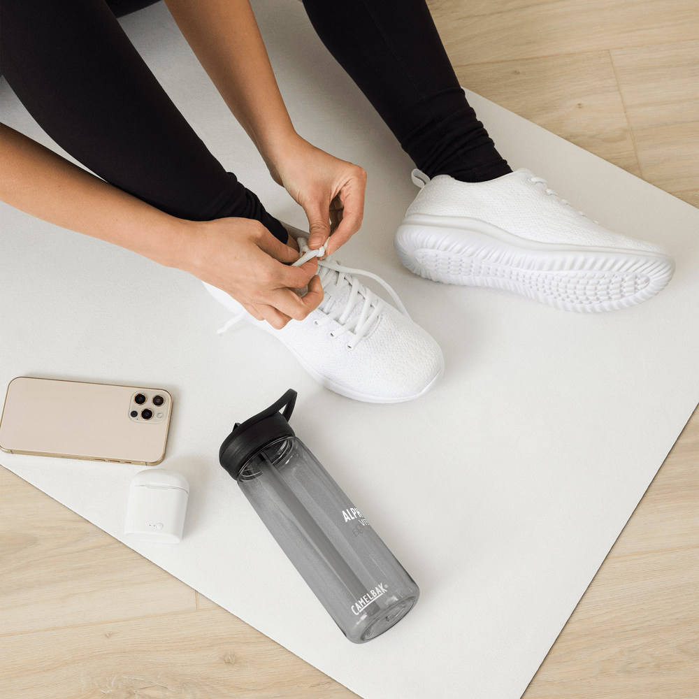 Alpha Omega Vitality premium sports water bottle next to a person tying their shoes on an exercise mat